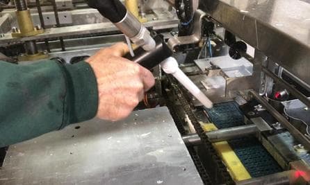 Sanitation tech dry-ice cleaning a food conveyor without water