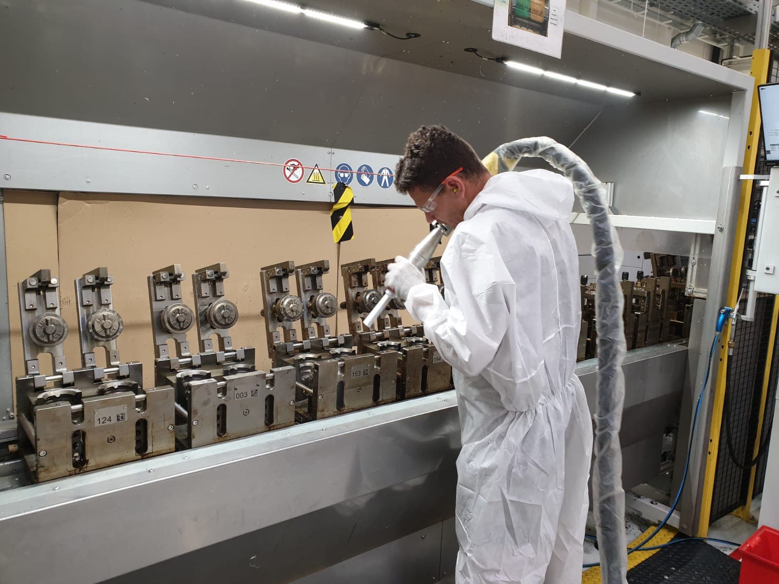 Operator performing dry-ice cleaning on a hot injection mold in the press
