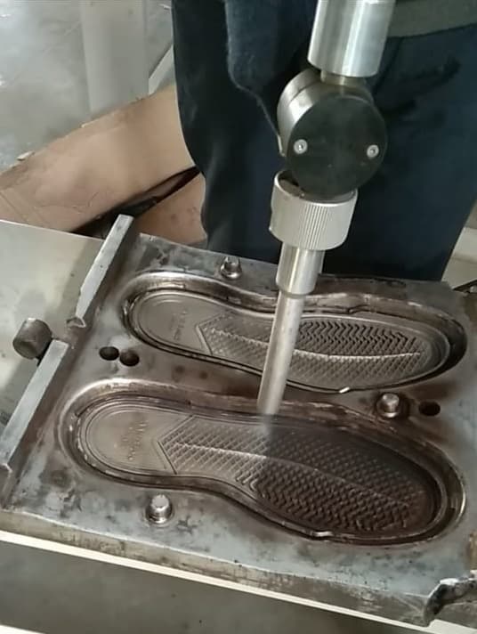 Operator cleaning a heated shoe mold cavity with CO₂